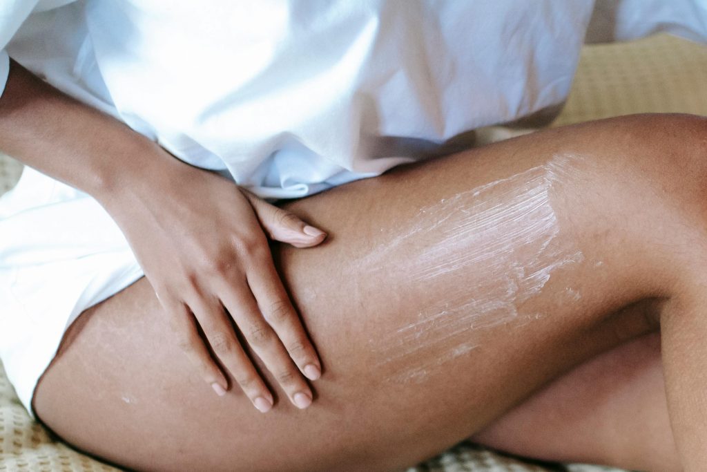 A woman gently applying moisturizing cream to her leg for skin care routine.
